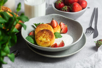 Syrniki Cheesecakes Appetizing cottage cheese pancakes with cream sauce, strawberries and mint in a...