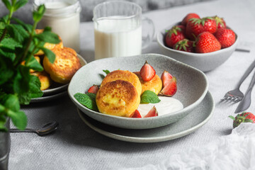 Syrniki Cheesecakes Appetizing cottage cheese pancakes with cream sauce, strawberries and mint in a...