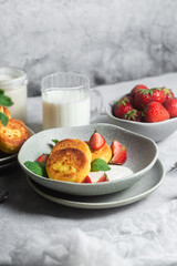 Syrniki Cheesecakes Appetizing cottage cheese pancakes with cream sauce, strawberries and mint in a plate. Breakfast