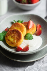 Syrniki Cheesecakes Appetizing cottage cheese pancakes with cream sauce, strawberries and mint in a plate. Breakfast