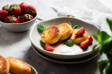 Syrniki Cheesecakes Appetizing cottage cheese pancakes with cream sauce, strawberries and mint in a...