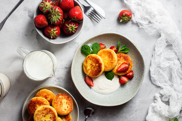 Syrniki Cheesecakes Appetizing cottage cheese pancakes with cream sauce, strawberries and mint in a plate. Breakfast