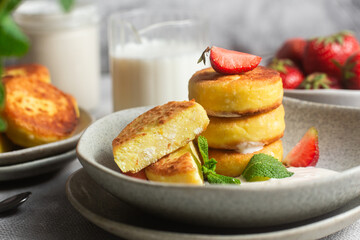 Syrniki Cheesecakes Appetizing cottage cheese pancakes with cream sauce, strawberries and mint in a...