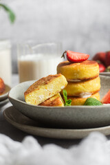 Syrniki Cheesecakes Appetizing cottage cheese pancakes with cream sauce, strawberries and mint in a plate. Breakfast