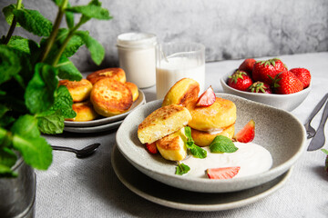 Syrniki Cheesecakes Appetizing cottage cheese pancakes with cream sauce, strawberries and mint in a...