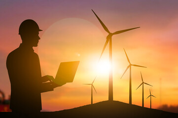 Engineering holding laptop wind turbine sunset