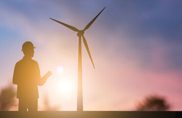 A silhouette engineer with wind turbine sunset background