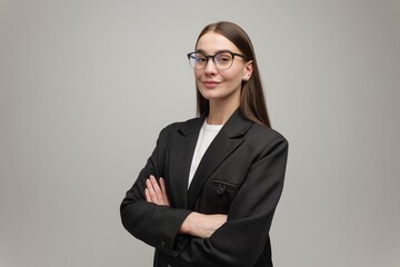 Confident young woman in a stylish black blazer stands gracefully against a simple background