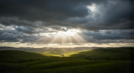 Obraz premium Expansive green landscape under dramatic cloudy sky with sunlight 