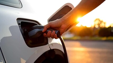Man charging electric car at public charging station, plugging in power cable in slow motion. Eco-friendly transportation, sustainable urban mobility, clean energy and modern electric vehicle
 - Powered by Adobe