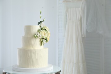 Delicious wedding cake with floral decor on table indoors, space for text