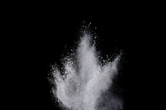 White powder or flour explosion isolated on black background.