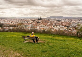 Person sitting on a bench overlooking the panorama of the city of Clermont Ferrand in France