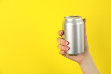 Woman with tin can on yellow background, closeup. Space for text