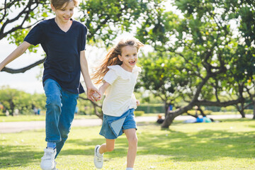 Fototapeta premium Brother and sister playing together at the park in the morning sunrise