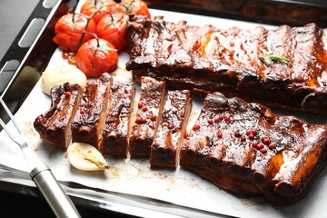 Delicious spare ribs, onion and sun dried tomatoes on baking tray, closeup