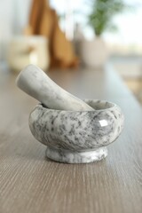 Marble mortar and pestle on wooden table in kitchen, closeup