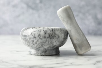 Mortar and pestle on white marble table, closeup
