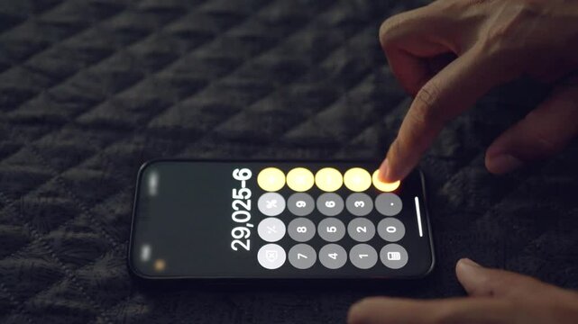 A person is using a calculator on their phone. The calculator is set to 6,265. The person is pressing the number 7