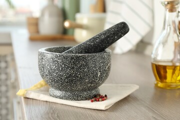 Stone mortar, pestle and spices on wooden table in kitchen