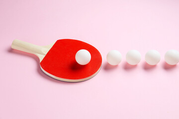 Ping pong racket and balls on pink background
