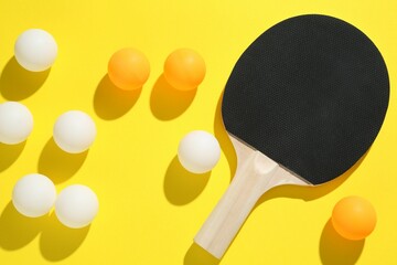 Ping pong racket and balls on yellow background, flat lay