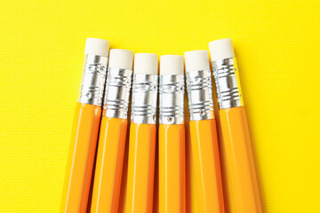 Pencils with erasers on yellow background, flat lay