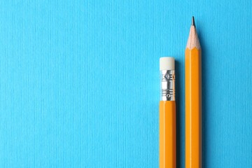 Graphite pencils on light blue background, top view. Space for text
