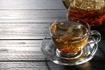 Refreshing herbal tea on black wooden table, closeup. Space for text