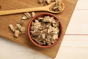 Pieces of dry chicory roots in bowl and spoon on wooden table, top view