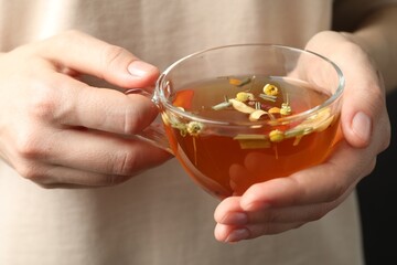 Woman with glass cup of aromatic herbal tea, closeup