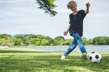 Little boy playing football in the garden with morning sunrise
