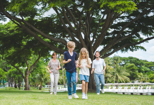 Happy family parent children having picnic outdoor activity. Enjoy happiness moment summer playing together including father mother son and daughter relaxing in the morning sunrise.