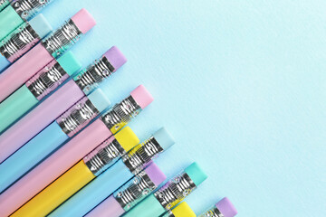 Graphite pencils with erasers on light blue background, flat lay. Space for text