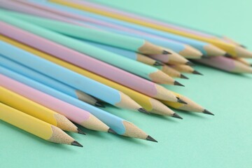 Many graphite pencils on turquoise background, closeup