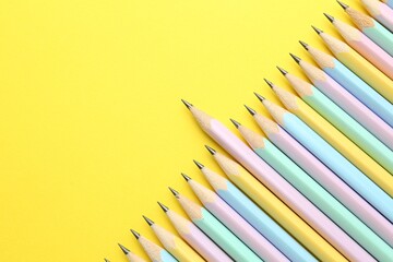 Many graphite pencils on yellow background, flat lay. Space for text