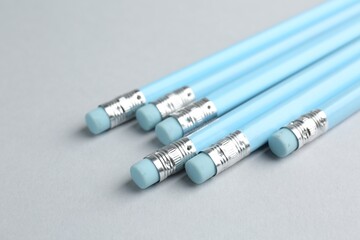 Many graphite pencils with erasers on light grey background, closeup
