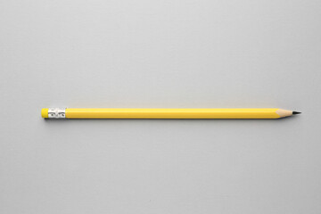 One graphite pencil on light grey background, top view