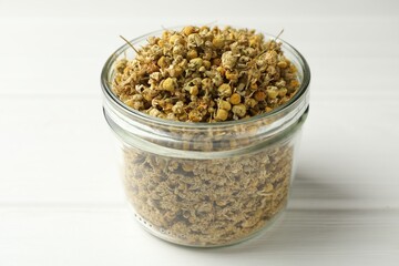 Dry chamomile flowers on white wooden table, closeup