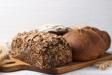 Fresh bread loaves and spikes on white wooden table, closeup