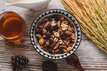 Overhead view of a rustic breakfast setting with a bowl of chocolate cereal mix, honey, and dried rice stalks on a wooden table. Healthy Morning.