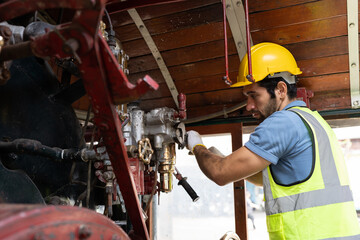 Locomotive repair garage, Mechanic, Engine Mechanic. Engineer checking, repairing, maintaining locomotive engine. Railway engineer and train wheel in train garage