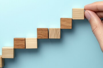 Woman hand arranging wooden blocks in a step stair pattern symbolizing business growth and success, with a blue background emphasizing a strategic process.