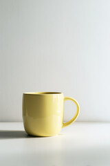 Yellow ceramic mug on a white surface against a neutral background  