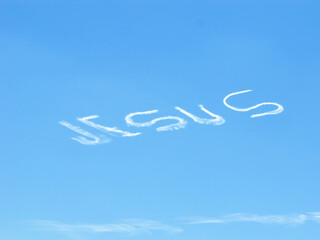 A skywriter has written the name "JESUS" in the sky, likely as a form of evangelism or religious expression.