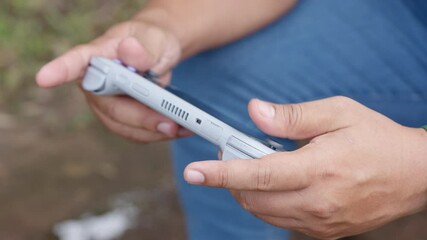 A person is holding a video game controller. The controller is grey and has a black and white design - Powered by Adobe