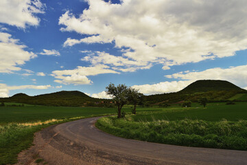 Country Road in Rolling Hills Under Shifting and Dramatic Weather Patterns