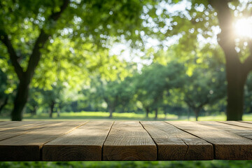 Fototapeta premium A rustic wooden table in focus with a blurred background of a serene park filled with vibrant green trees and sunlight filtering through.