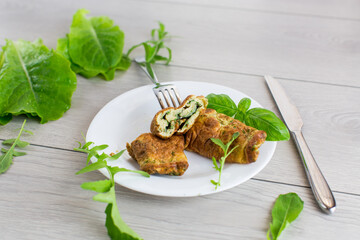 Omelette roll with greens on top on a wooden table