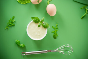 Ingredients for mayonnaise with basil and a whisk from above